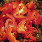 Paski czerwonej papryki i krążki pepperoni włożone do gulaszu